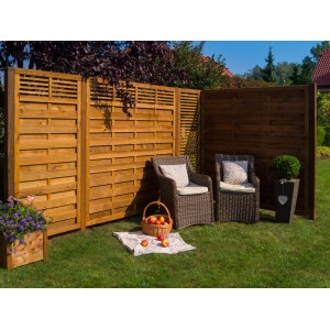 Drewniany płot i zestaw mebli ogrodowych na trawniku. Parawan i wiklinowe krzesła do ogrodu.