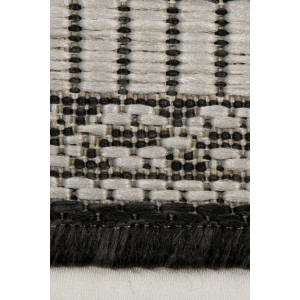 Zbliżenie dywanu t.b.t. z krótkim włosiem, wzór w kolorze czarnym i beżowym.