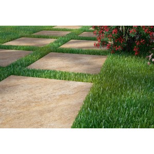 Kwadratowe, beżowe płyty tarasowe ułożone między trawnikami.