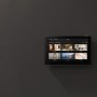 Monitor Ezviz z baterią (17,8 cm) do monitoringu kamer na szarej ścianie w sypialni.