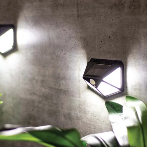 Świecący kinkiet solarny t.b.t. na szarej ścianie. Widoczny panel słoneczny i czujnik ruchu.