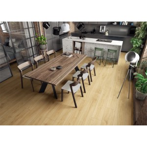 Ułożone, jasne panele podłogowe t.b.t. w kuchni z jadalnią, ze stołem i wyspą kuchenną.