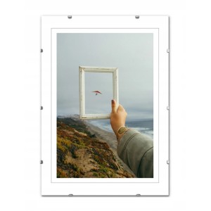 Ramka t.b.t. z ręką trzymającą małą ramkę na tle nadmorskiego krajobrazu.