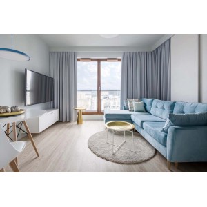 Salon z niebieskimi zasłonami na karniszu, pasującymi do kanapy.