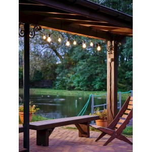 Dekoracyjny łańcuch świetlny jako lampa zewnętrzna nad miejscem do siedzenia z ławką i krzesłem.