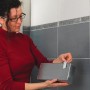 Kobieta przykleja pojemnik do ściany za pomocą taśmy klejącej t.b.t.