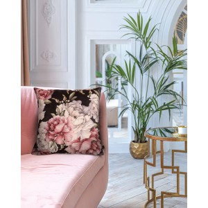 Dekoracyjna poduszka t.b.t. z kwiatowym wzorem na różowej sofie.