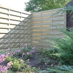 Drewniany płot t.b.t. w ogrodzie z rabatą kwiatową. Drewniany płot osłonowy.
