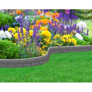 Szara obrzeże trawnikowe t.b.t. z kamienia, zakrzywiony kształt, w ogrodzie z rabatą kwiatową.