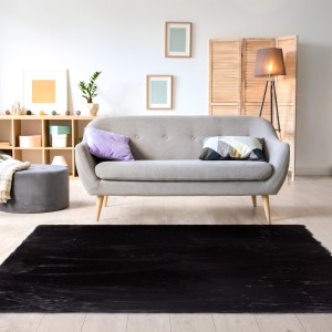 Czarny, prostokątny dywan z długim włosiem t.b.t. w salonie.
