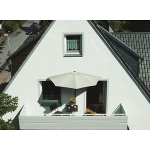 Beżowy parasol balkonowy na balkonie ze stołem i krzesłami.