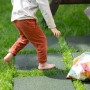 Dziecko boso na zielonych płytach placu zabaw w ogrodzie. Sprzęt do zabawy na zewnątrz.