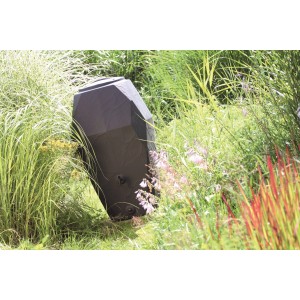 Ciemny zbiornik na deszczówkę t.b.t. w ogrodzie, otoczony roślinami.