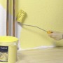 Użycie wałka LUX Goldfadenwalze 12 cm do malowania ściany na żółto. Wiadro z farbą na pierwszym planie.