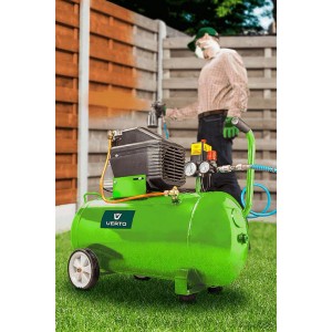 Zielony kompresor Verto rozpyla farbę na ogrodzeniu w ogrodzie.