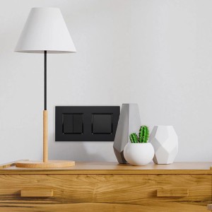 Czarny włącznik i przycisk t.b.t. na ścianie, obok lampy i dekoracji.