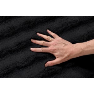 Czarny, puszysty dywan z długim włosiem; dłoń dotyka miękkiej powierzchni.