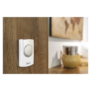 Biały dzwonek do drzwi t.b.t. zamontowany na drewnianych drzwiach.