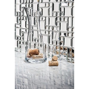 Błyszczące płytki mozaikowe t.b.t. jako okładzina ścienna, w połączeniu ze szklanym wazonem.