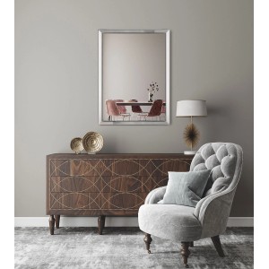 Prostokątne lustro do garderoby t.b.t. ze srebrną ramą nad komodą i fotelem.