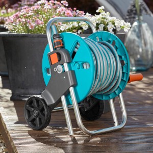 Zestaw wózka na wąż Gardena CleverRoll S z wężem 20 m i akcesoriami na drewnianym tarasie.