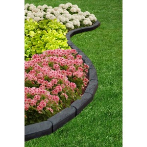 Zakrzywiona szara plastikowa obrzeże trawnikowe obramowująca rabatę kwiatową z różowymi i białymi kwiatami.