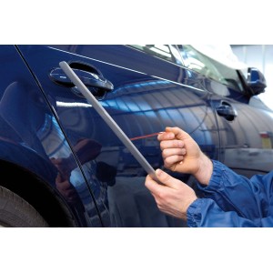 Aplikacja taśmy klejącej t.b.t. za pomocą aplikatora na niebieskim samochodzie.