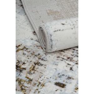 Zrolowany dywan z krótkim włosiem o abstrakcyjnym wzorze w odcieniach bieli, beżu i brązu.