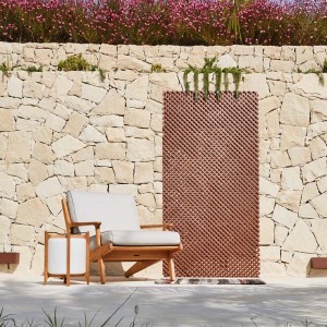 t.b.t. parawan ogrodowy i fotel przed kamiennym murem z kwiatami.