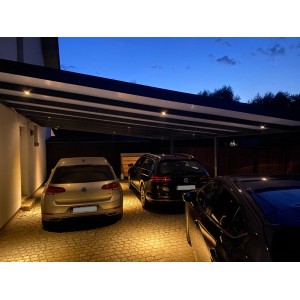 Nowoczesny garaż/wiata garażowa z trzema samochodami zaparkowanymi w nocy.