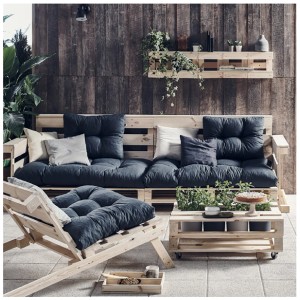 Scena tarasowa z meblami z palet: sofa, leżanka i stół z roślinami.