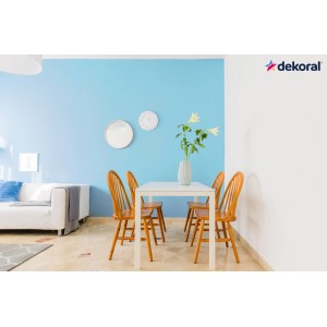 Salon z niebieską ścianą pomalowaną farbami dekoracyjnymi i białym stołem jadalnym z krzesłami.