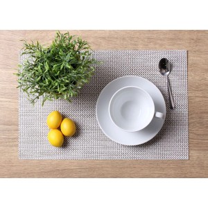 Podkładka na drewnianym stole z filiżanką, spodkiem, łyżką, cytryną i rośliną.