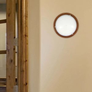 Okrągła lampa sufitowa t.b.t. z drewnianą ramą na beżowej ścianie.
