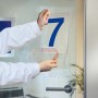 Osoba przykleja niebieską cyfrę 7 do szklanych drzwi za pomocą taśmy t.b.t.
