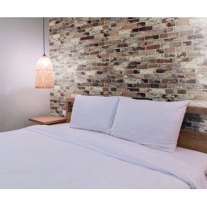 Okładzina ścienna Ceramics Tisa o wyglądzie cegły za łóżkiem w sypialni.