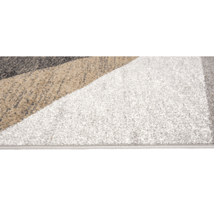 Zbliżenie dywanu z krótkim włosiem o geometrycznym wzorze w odcieniach szarości, beżu i bieli.