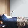 Farba ścienna t.b.t. w jasnoniebieskim odcieniu w sypialni z łóżkiem i lampą.