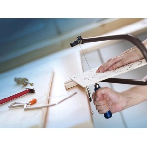 W użyciu wyrzynarka LUX Classic: zbliżenie dłoni, obrabianego przedmiotu i piły podczas cięcia.