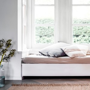 Jasny parapet z poduszkami i dekoracją w białym pokoju.