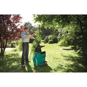 Rozdrabniacz elektryczny Bosch AXT 25 TC z mężczyzną wrzucającym odpady ogrodowe.