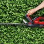 Akumulatorowe nożyce do żywopłotu Einhell GC-CH 1855/1 Li Kit w kolorze czerwono-czarnym podczas cięcia żywopłotu.