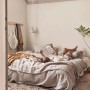 Kobieta czyta w łóżku, neutralny kolor ściany. Kolorowe farby do ścian dla przytulnej atmosfery.