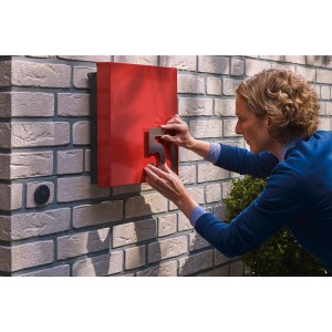 Kobieta przyczepia numer domu do czerwonej skrzynki pocztowej za pomocą samoprzylepnych t.b.t. Wieszaki samoprzylepne.