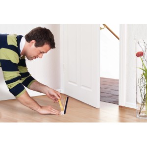 Mężczyzna mocuje białą uszczelkę do drzwi Tesamoll do nierównych podłóg.