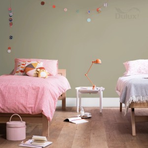 Pokój dziecięcy z farbą ścienną w delikatnym zielonym kolorze. Dwa łóżka i girlanda świetlna dekorują pokój.