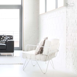 Biała ściana pomalowana farbą do ścian t.b.t. i biały fotel w nowoczesnym salonie.