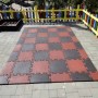 Wzór szachownicy z czerwonych i czarnych mat placu zabaw jako ochrona przed upadkiem dla sprzętu zabawowego.