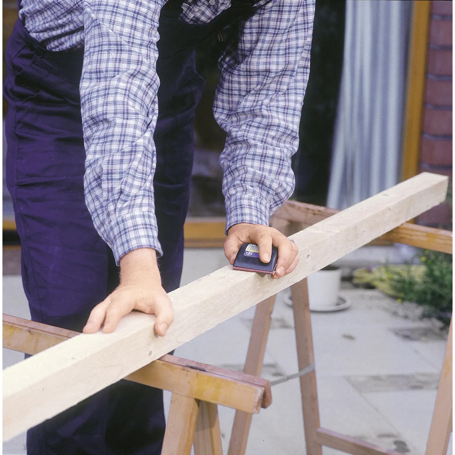 Rzemieślnik szlifuje drewno za pomocą klocka ściernego LUX 70x130 mm dla precyzyjnych rezultatów.