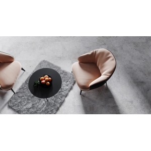 Beżowe fotele i czarny stolik na szarych płytkach podłogowych. Przytulny kącik.